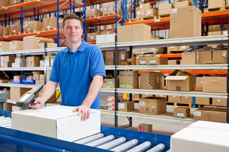 Warehouse worker in blue shirt packing boxes on conveyor belt system